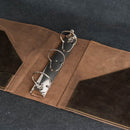 A close-up of an open brown leather ring binder or organizer